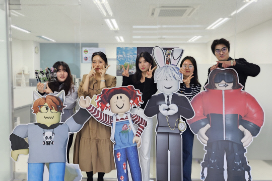 메타버스 플랫폼 로블록스를 배경으로 펼쳐지는 신개념 메타버스 장편 게임 애니메니션 '블록나라의 알로스' 시리즈를 선보여 시즌 9까지 방영하며 알파 세대들에게 호응받고 있는 미디어 스타트업 '타이밍포올'의 제작진들이 《희대의 NOW 구독중》 인터뷰를 마치고 기념 촬영을 하고 있다. 오른쪽부터 광운대 OTT 미디어 전공 이희대 교수, '타이밍포올'의 윤지수 과장, 유하민 대리(PD), 이지영 주임(PD), 맹세은 주임(PD)이 '블록나라의 알로스' 주요 캐릭터들과 함께 포즈를 취하고 있다.